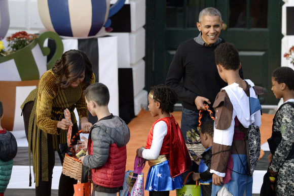 31일(현지시간) 미국 워싱턴DC 백악관에서 열린 핼러윈 행사에서 오바마 대통령 부부가 아이들에게 사탕을 나눠주고 있다. EPA 연합뉴스