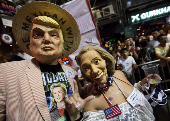 31일(현지시간) 홍콩 거리에서 미국의 대선후보인 힐러리 클린턴과 도널드 트럼프 가면을 쓴 사람들이 핼러윈 데이를 맞이하여 축제를 즐기고 있다. EPA 연합뉴스