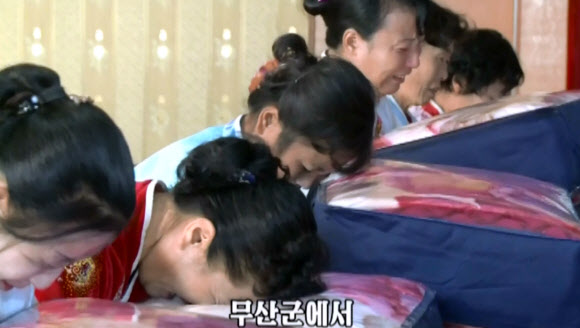 북한 함경북도 수해지역 이재민들이 김정은 노동당 위원장이 전달한 담요를 전달받는 모습. 조선중앙TV는 김정은이 주민들에게 담요를 보냈다는 소식을 3일 전하면서 주민들이 ”친 어버이의 육친적 사랑에 뜨거운 격정을 금치 못했다”고 밝혔다.  연합뉴스