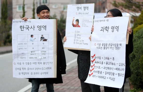 대학수학능력시험일인 17일 전북 전주시 완산구 기전여고 앞에서 비선 실세의 국정농단 사태를 수능 문제에 비유한 풍자 피켓을 든 학생들이 응원전을 펼치고 있다. 전주 연합뉴스