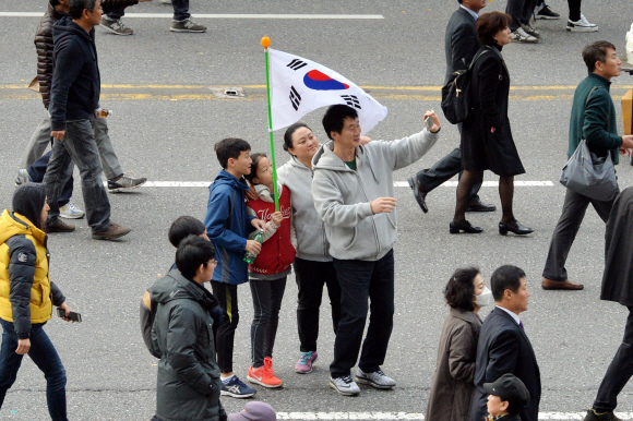 19일 오후 서울 광화문광장 일대에서 열린 제4차 촛불집회에 참가하기 위해서 세종로를 따라 이동하던 한 가족이 함께 인증샷을 남기고 있다.   손형준 기자 boltagoo@seoul.co.kr
