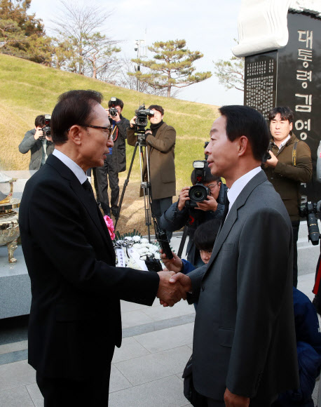 이명박 전 대통령(왼쪽)이 고(故) 김영삼 전 대통령 서거 1주기를 하루 앞둔 21일 오후 서울 동작구 국립서울현충원에서 김 전 대통령 묘소를 참배한 뒤 김 전 대통령의 차남 김현철 고려대 지속발전연구소 연구교수와 악수하고 있다.  연합뉴스