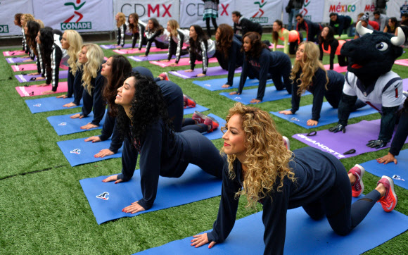 20일(현지시간) NFL 휴스턴 텍슨스의 치어리더들이 멕시코의 멕시코시티 천사의 탑 아래서 요가수업을 하고 있다. NFL은 히스패닉 팬들을 끌어들이기 위해 휴스턴 텍슨스와 오클랜드 레이더스의 경기를 멕시코시티에서 개최하기로 했다. AFP 연합뉴스