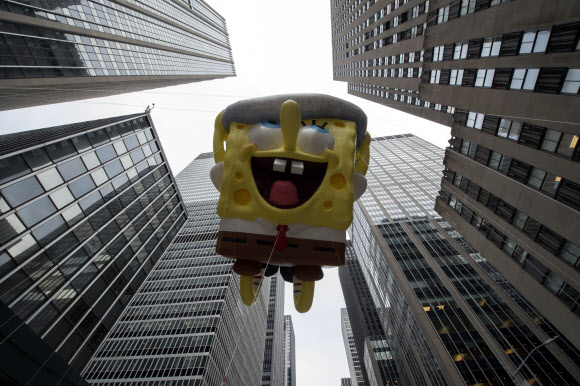 24일(현지시간) 미국 뉴욕 맨해튼에서 ‘메이시스 추수감사절 퍼레이드’가 열린 가운데 인기 캐릭터 ‘스폰지밥’ 대형 풍선이 등장하고 있다. AP 연합뉴스