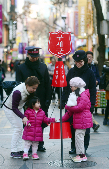지난해 12월 1일 서울 명동에서 모금활동을 시작한 구세군의 자선냄비에 관광객들이 돈을 넣고 있다.   정연호 기자 tpgod@seoul.co.kr