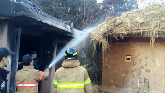 소방관들이 추모관 옆 초가지붕으로 번진 화재를 진압하고 있다. 구미 연합뉴스