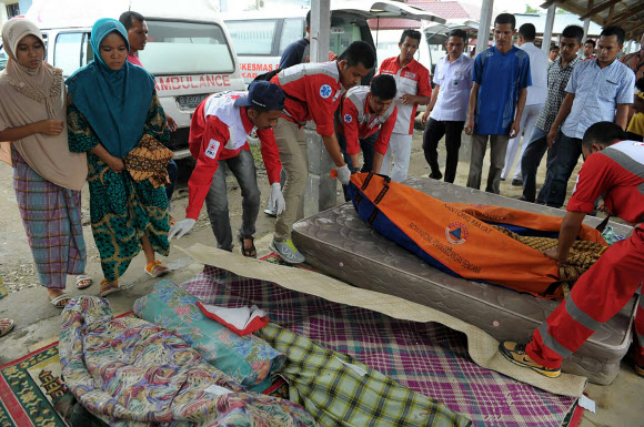 7일(현지시간) 인도네시아 아체주 피디에자야에서 주민들이 사망자를 확인하고 있다. 규모 6.5의 이번 강진으로 인해 사망자가 최소 92명으로 늘어났으며 부상자는 약 300명에 달하고 있다. AFP 연합뉴스