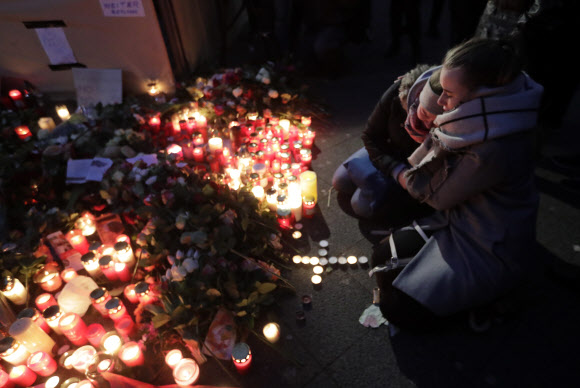 20일(현지시간) 독일 베를린의 시민 두 명이 베를린에 임시로 설치된 추모소에 촛불을 켜고 서로 껴안은 채 위로하는 모습. 베를린 AP 연합뉴스