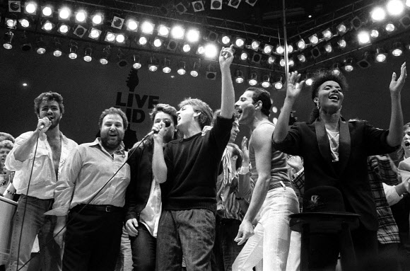 　25일(이하 현지시간) 세상을 떠난 조지 마이클(왼쪽부터)이 1985년 7월 13일 영국 런던 웸블리 구장에서 열린 아프리카 기아 돕기 공연 ´라이브 에이드´ 막바지 이 공연 기획자인 하비 골드스미스, U2의 리더 보노, 폴 매카트니, 공연 기획자 밥 게돌프와 그룹 ´퀸´의 프레디 머큐리 등과 어울려 노래하고 있다.  AP 자료사진 
