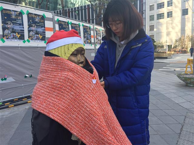 평화의 소녀상 지킴이로 활동하고 있는 대학생 이소영씨가 27일 서울 종로구 옛 일본대사관 앞 소녀상의 겨울옷 매무새를 다듬어 주고 있다.