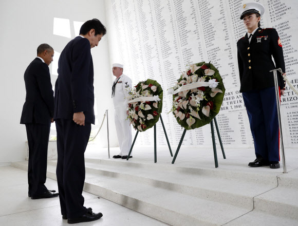 아베 신조 일본 총리(왼쪽 두번째)와 버락 오바마 미국 대통령(왼쪽)이 27일(현지시간) 하와이 진주만에 있는 애리조나기념관을 찾아 헌화한 뒤 진주만 공습 희생자들을 추모하고 있다. AP 연합뉴스