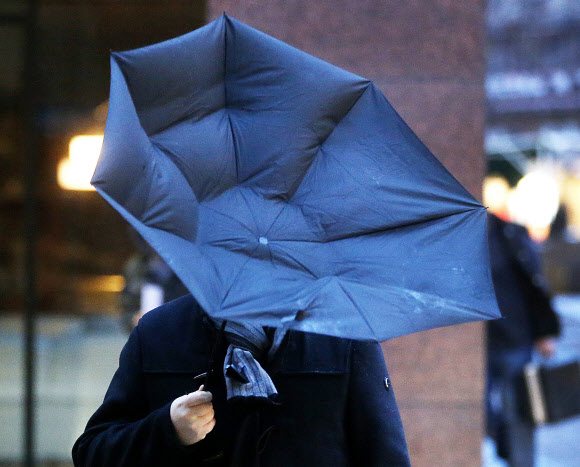 한 남성이 13일(현지시간) 독일 프랑크푸르트 시내를 걷다가 강풍에 우산이 뒤집어져 당황하고 있다. AP 연합뉴스