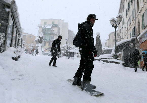 지중해에 있는 프랑스 코르시카 섬에 17일(현지시간) 폭설로 거리가 눈으로 뒤덮인 가운데 한 시민이 스노 보드를 타고 이동을 하고 있다. AFP 연합뉴스