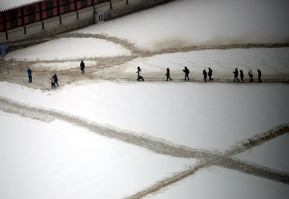 금요일이자 대한(大寒)인 20일 중부지방을 중심으로 많은 눈이 내리는 가운데 경복궁에 관광객들을 위해 치운 길로 관광객들이 이동하고 있다. 연합뉴스