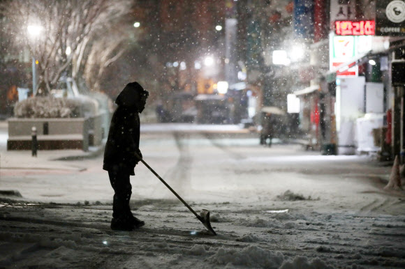 24절기상 대한(大寒)인 20일 오전 서울 광화문 인근의 한 빌딩에서 관계자가 밤사이 내린 눈을 치우고 있다.  연합뉴스