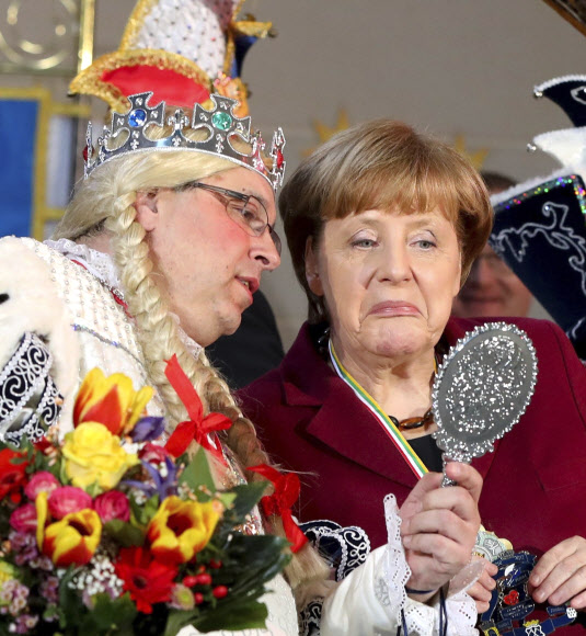 앙겔라 메르켈 독일 총리(오른쪽)가 23일(현지시간) 베를린의 총리관저에서 열린 홈부르크 카니발 클럽 환영회에서 클럽 멤버와 함께 거울을 들여다보고 있다. AP 연합뉴스