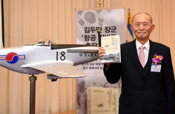 대한민국 공군의 살아 있는 전설이자 11대 공군참모총장을 지낸 김두만 장군의 평전 ‘항공 징비록’ 출판 기념회가 25일 서울 동작구 대방동 공군회관에서 열린 가운데 행사에 참석한 김 장군이 자신의 평전을 들어 보이고 있다. 아래 사진은 6·25전쟁 당시 F51 전투기에 탑승한 김 장군의 모습. 연합뉴스