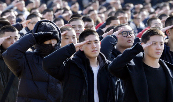 JYJ 김준수(오른쪽)와 빅뱅 탑(왼쪽)이 9일 논산훈련소 입소 행사에 참석해 경례하고 있다.  연합뉴스