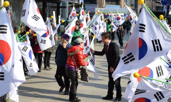 3·1절을 하루 앞둔 28일 박겸수(오른쪽) 강북구청장이 강북구청 사거리에서 열린 ‘나라사랑 태극기 달기 캠페인’에 참석해 시민들에게 태극기를 나눠 주는 모습.<br>이언탁 기자 utl@seoul.co.kr