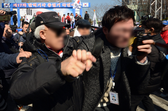 10일 서울 헌법재판소 앞 안국역에서 보수단체 회원이 탄핵이 인용되자 흥분한 상태로 기자를 폭행하고 있다.  박지환 기자 popocar@seoul.co.kr