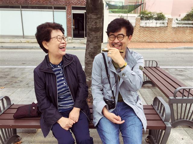 진해의 한 거리에서 엄마(왼쪽)와 함께 환히 웃고 있는 김탁환(오른쪽) 작가. 김 작가는 “독자들도 저마다의 골목을 엄마와 걷고, 이야기하고, 웃었으면 좋겠습니다. 더 늦게 전에, 부디!”라고 당부했다. 난다 제공