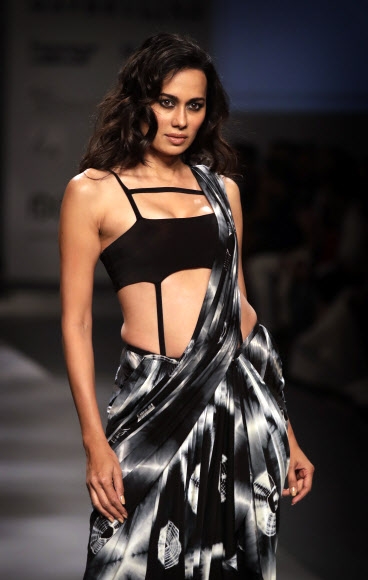 15일(현지시간) 인도 뉴델리에서 열린 2017 인도 패션위크에서 인도 전통의상 ‘사리(saree)’를 모티브로 한 드레스를 입은 모델이 런웨이를 걷고 있다.<br>AP 연합뉴스