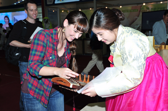 ‘가야금 연주·제작 체험 프로그램’에 참가한 외국인 관광객이 가야금 현을 손끝으로 튕겨 보며 신기해하고 있다.<br>고령군 제공