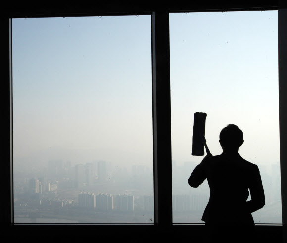 미세먼지 농도가 수도권·강원 영서·충청·전북에서 ’나쁨’ 수준을 보일 것으로 예상된 17일 오전 서울 63빌딩에서 한 직원이 창문을 닦고 있다.  연합뉴스