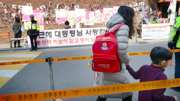 17일 서울 삼성동 박근혜 전 대통령 자택 인근에 등하교시간 동안 집회금지 명령이 내려진 가운데 한 어린이가 엄마와 함께 하교를 하고 있다.  정연호 기자 tpgod@seoul.co.kr