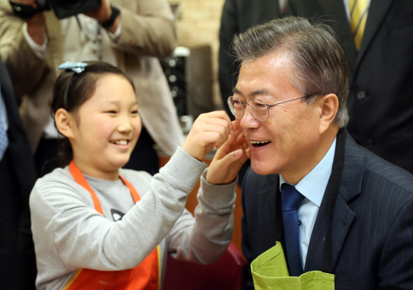 22일 서울 영등포구 대영초등학교 학생이 케익 만들기 실습을 마친 더불어민주당 문재인 전 대표 얼굴에 스티커를 붙이고 있다. 이종원 선임기자 jongwon@seoul.co.kr