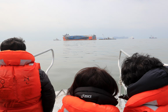 세월호 미수습자 가족들이  26일 오전 전남 진도군 세월호 사고 수습 인근에서 반잠수선에 실려 온전히 모습을 드러낸 세월호를 바라보고 있다. 2∼4일로 예상되는 배수를 거치면 세월호는 반잠수선과 고박을 단단히 하고 목포 신항을 향해 ’마지막 항해’에 나선다.  연합뉴스