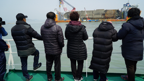 8일 오전 전남 진도군 세월호 사고해역 인근 선박 위에서 열린 미수습자의 조기 수습을 기원하는 4대 종단 종교행사가에 참석한 미수습자 가족들이 세월호를 바라보고 있다. 2017. 03. 28 [해양수산부 제공]