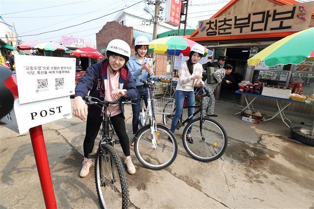 28일 인천 강화군 교동도에서 교동도 대룡시장을 찾은 자전거 여행객이 스마트워치로 전자스탬프를 받고 있다. KT 제공