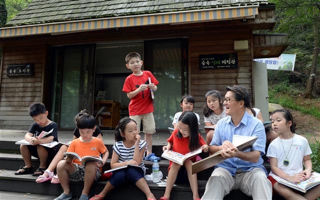 유 구청장(오른쪽 두 번째)이 지난해 8월 관악산 숲속 도서관에서 아이들과 책을 읽으며 이야기를 나누고 있다. <br>관악구 제공