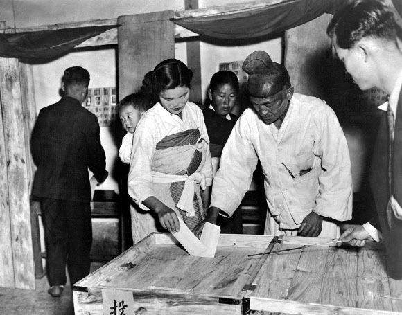 국가기록원이 11일 공개한 ‘기록으로 보는 그 시절 선거풍경’에서는 1948년부터 1990년대까지의 다양한 선거 현장 모습을 담았다. 사진은 1948년 아이 업은 여인과 할아버지가 투표를 하는 모습.  국가기록원 제공