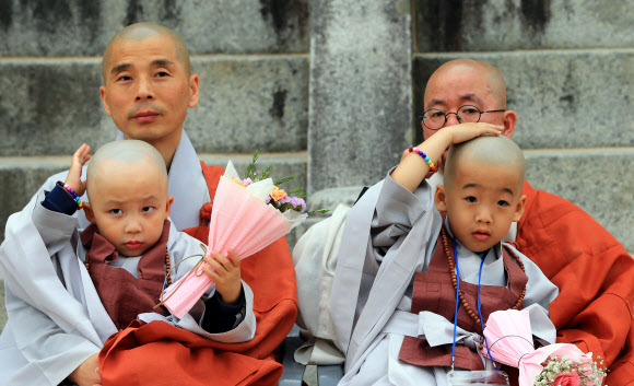 부처님 오신 날을 앞두고 14일 대한불교조계종 제3교구 본사 설악산 신흥사가 마련한 동자승 단기출가 수계식에 참가한 불교유치원 어린이들이 스님들 품에 안겨 삭발한 머리가 이상한 듯 자꾸만 만져보고 있다.  연합뉴스