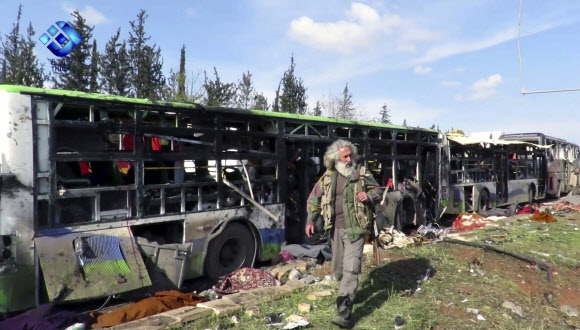 무장한 시리아인이 15일(현지시간) 시리아 알레포 인근 라시딘 외곽에 처참하게 부서진 버스 행렬 사이를 살펴보고 있다. 정부군 관할 지역으로 철수하던 시아파 주민이 탄 호송버스 행렬을 겨냥한 차량 자폭 공격으로 어린이를 포함해 최소 100명이 숨졌다고 CNN은 전했다. 이들은 시리아군과 반군 포위 지역 철수 협상에 따라 알푸아, 카푸라야를 떠나 알레포의 정부군 지역으로 이동 중이었다. 알레포 AP 연합뉴스