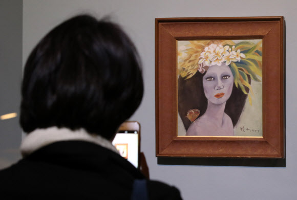 18일 오전 경기도 과천시 국립현대미술관에서 열린 고 천경자 화백 미인도 언론공개 행사에서 한 기자가 미인도를 촬영하고 있다. 국립현대미술관은 이날 언론 공개를 시작으로 19일부터 과천관에서 열리는 ’소장품전: 균열’을 통해 미인도를 일반 공개한다.   미인도 위작 논란과 관련해 검찰은 지난해 12월 미인도가 진품이라고 발표했지만 유족측은 이에 맞서 항고한 상태다.  연합뉴스