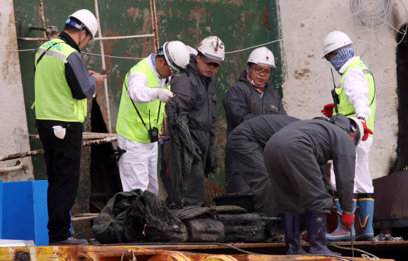 18일 오후 목포신항에 거치된 세월호 좌현 부분에서 관계자들이 수색을 한 뒤 가방으로 보이는 유류품을 정리하고 있다.  연합뉴스
