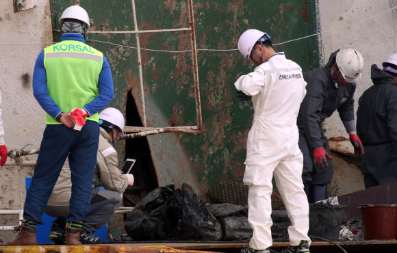 18일 오후 목포신항에 거치된 세월호 좌현 부분에서 관계자들이 수색을 한 뒤 가방으로 보이는 유류품들을 조사하고 있다.  연합뉴스