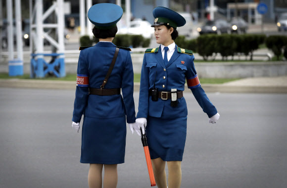 북한 여자 교통 경찰들이 19일(현지시간) 평양에서 교대 근무를 하기 위해 교통 안내에 사용하는 LED 봉을 주고 받고 있다. AP 연합뉴스