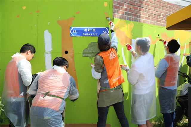 지난 29일 경기 시흥시 매화동 골목길에서 호반건설 직원들이 벽화 그리기 봉사활동을 하고 있다. 호반건설 제공