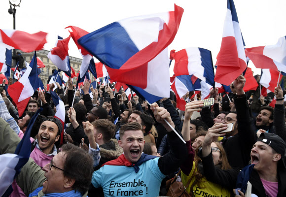7일(현지시간) 프랑스 파리 루브르 박물관 앞 광장에 마크롱 지지자들이 프랑스 삼색 국기를 휘날리며 기뻐하고 있다. AFP 연합뉴스