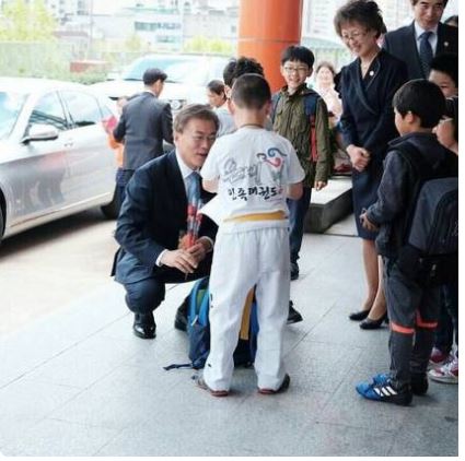 사인 종이 찾는 초등학생을 쪼그려 앉아 기다리는 문재인 대통령