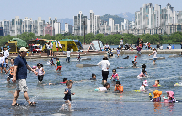 전국적으로 때이른 더위가 기승을 부린 21일 오후 서울 영등포구 여의도 물빛광장을 찾은 시민들이 물놀이를 즐기며 더위를 식히고 있다.  손형준 기자 boltagoo@seoul.co.kr