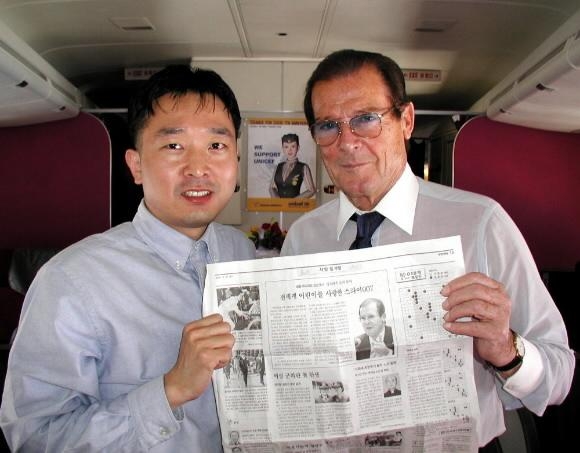 2001년 4월 로저무어(오른쪽)가 로스앤젤레스행 아시아나 항공기내에서 본사 이도운기자와 함께 자신의 활동상을 보도한 대한매일을 펼쳐보이고 있다. 서울신문 포토DB