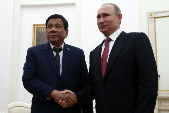 로드리고 두테르테(왼쪽) 필리핀 대통령과 블라디미르 푸틴 러시아 대통령이 23일(현지시간) 모스크바 크렘린궁에서 정상회담을 하기 전 악수를 나누고 있다. 이날 민다나오섬에서 반군과 정부군이 교전했다는 보고를 받은 두테르테 대통령은 계엄령을 발동하고 급거 귀국길에 올랐다. 모스크바 EPA 연합뉴스