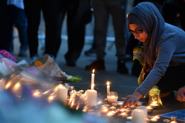 지난 22일 영국 맨체스터에서 발생한 테러로 최소 22명이 사망한 가운데 한 여성이 희생자들을 추모하는 촛불 앞에 앉아 있다. AFP 연합뉴스