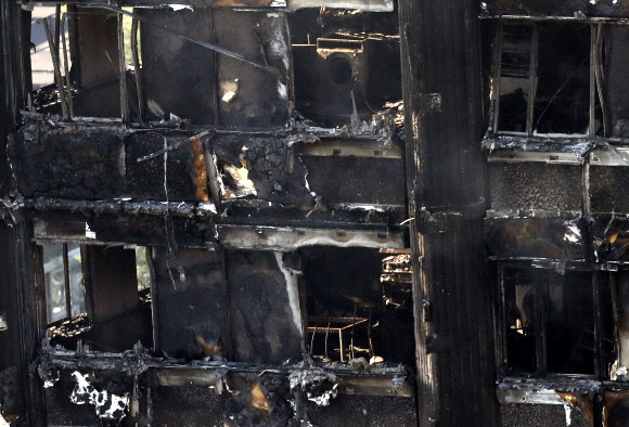 14일(현지시간) 새벽 영국 런던 시내에서 발생한 화재로 까맣게 타버린 24층짜리 아파트 건물이 15일 모습을 드러냈다. AP 연합뉴스