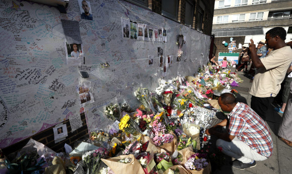 ‘런던 화재’ 희생자 애도하는 꽃다발과 메시지 보는 시민들